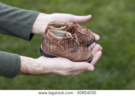 Dirty hands holding a pair of old childrens shoes
