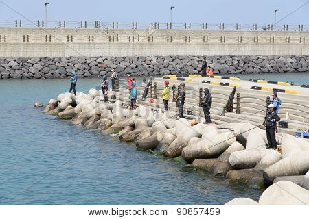 Jeju-do, Korea - April 08, 2015: Fishermen On A Breakwater