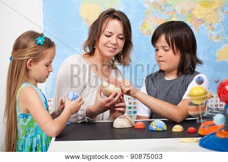 Kids and teacher in science class study the solar system - examining the planets from a scale model