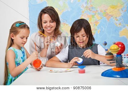 Kids making a scale model of the solar system in science class - helped by their teacher
