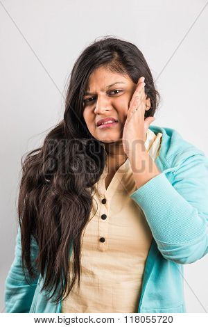 Closeup portrait young indian woman with sensitive tooth ache problem about to cry from pain touchin