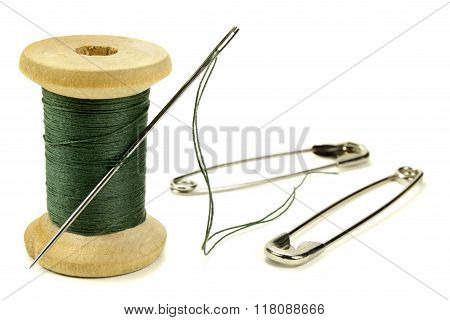 Wooden Coil With Threads, Needle And Safety Pin For Sewing On A White Background