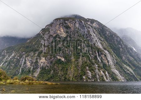 Fjords of Milford Sound South Island New Zealand. Huge fjord covered with water and mist on a rainy day
