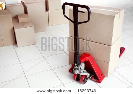 Fork pallet truck with stack of cardboard boxes indoors