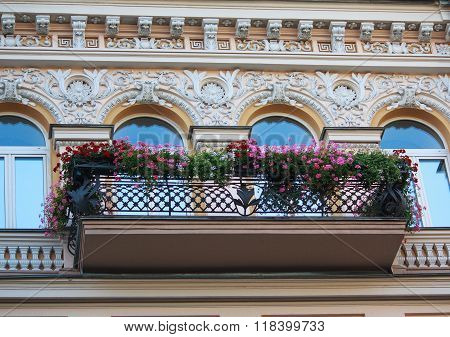 Balcony With Flowers And Facade Of The Building In Classical Style. Architecture