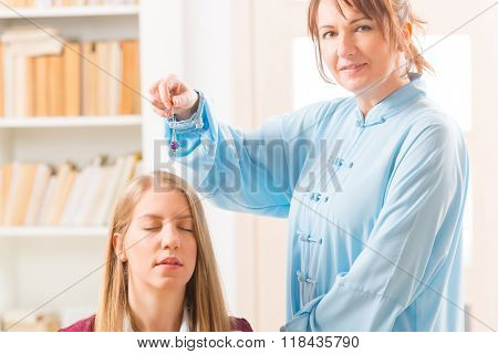 Alternative medicine therapist using pendulum to make a diagnosis