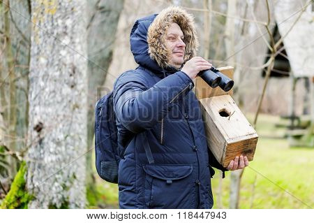 Ornithologist with binoculars and bird cage in the park