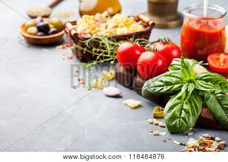 Italian food background with vine tomatoes, basil, spaghetti, olives Ingredients on stone table Copy