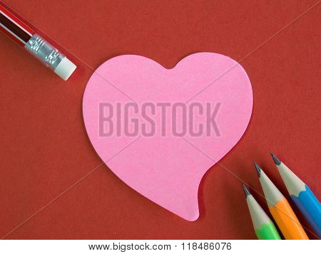 Pink Heart-shaped Memorandum On Red Paper With Colorful Pencils And Eraser