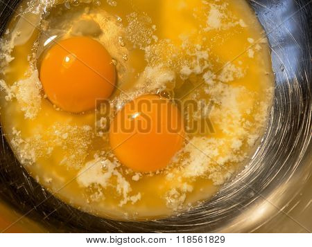 Hot butter and two eggs in steel scratched bowl