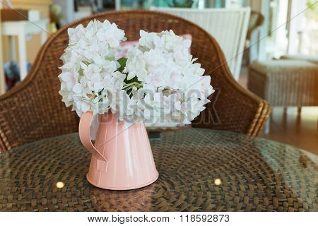 White Plastic Flowers In Pink Flower Vase On The Rattan Weave Table Decorated Interior In Cafe