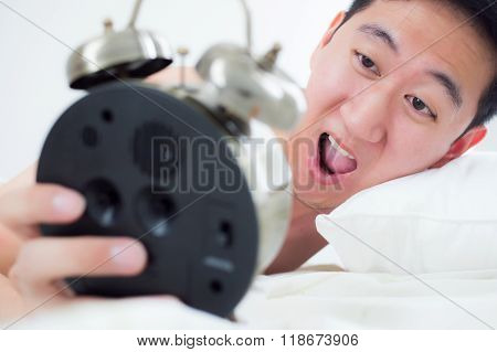Young Man On His Bedside, Knowing That He Overslept And Late For His Schedule