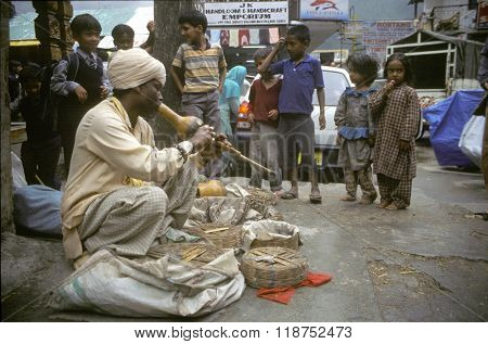 VASHISHT, INDIA - JULY 5, 2006 - A snake charmer draws a crowd with his cobras in baskets in Uttar Pradesh.