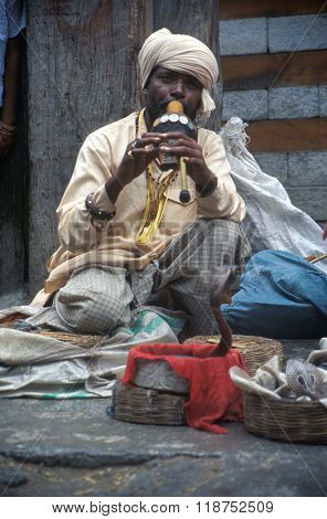 VASHISHT, INDIA - JULY 5, 2006 - A snake charmer draws a crowd with his cobras in baskets in Uttar Pradesh.