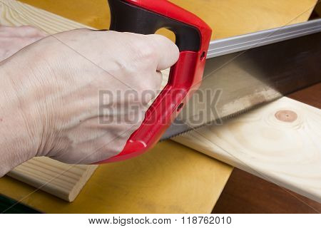 Close Up Of Builders With Arm Saw Sawing Board