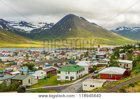 Mighty fjords with mountains covered by snow rise above the town of Olafsfjordur, Northern Iceland