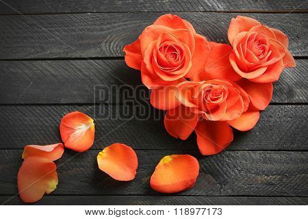 Fresh red roses buds in shape of heart on wooden background