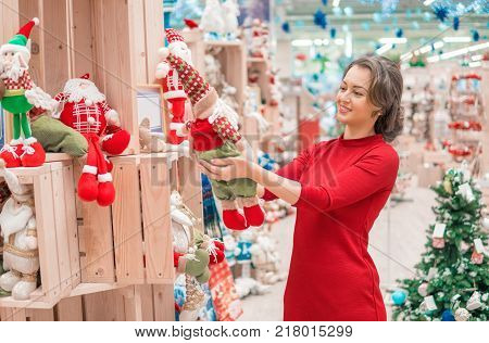 Cheerful happy customer girl choosing gifts for Christmas and New Year. She is holding Santa toys. Happy moments. Family care