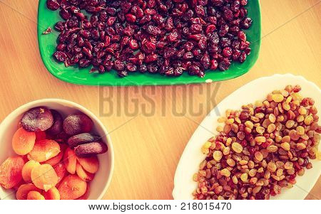Delicacies dry fruits cake additives concept. Plates with dried cranberries apricots and raisins.