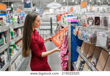Young female driver buys warning triangle in the supermarket car department. Safety shopping