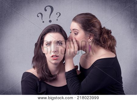 A teenager girl looking confused with drawn question marks above the head, while a girlfriend whispers something in her ear concept.