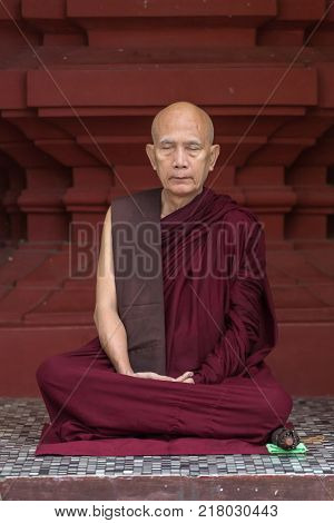 Yangon, Myanmar - September 27, 2016: Portrait of unidentified buddhist monk meditating in Shwedagon pagoda in Yangon, Myanmar