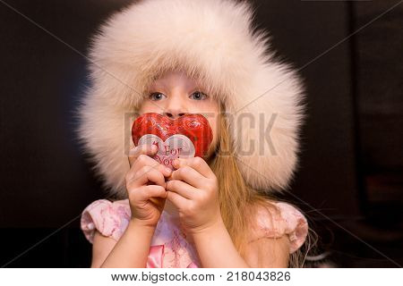 girl with heart. cute little girl in a fur hat holds the heart of love. Valentine's Day