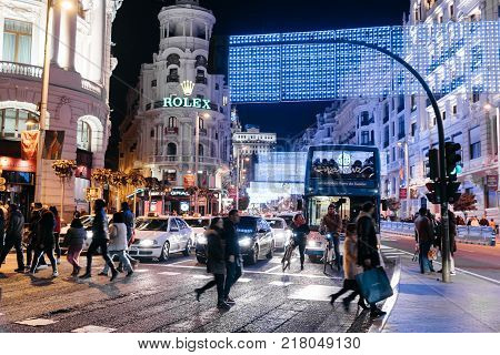 Madrid, Spain - December 8, 2017: People crossing the Gran Via Street in Madrid at night on Christmas time.
