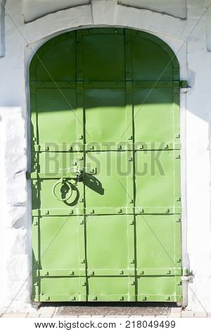 Vintage metal green door in the white house in the old town