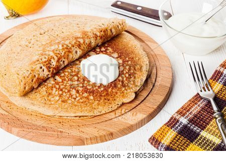 Traditional Russian blini with sour cream close-up. Homemade yeast pancakes with healthy wholegrain flour