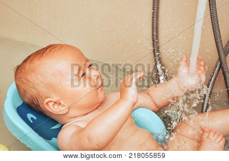 Adorable baby boy taking bath, child playing with wather