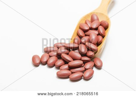 Ferrous Fumarate with Vitamins on a wooden spoon and on a white background