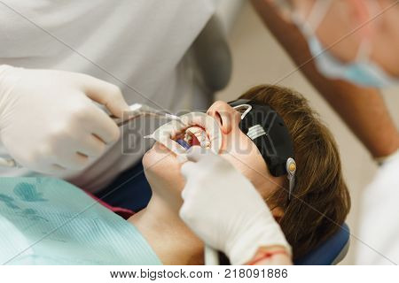 Process Of Preparing And Installing Dental Ceramic Crown. Male Professional Dentist And Female Assis