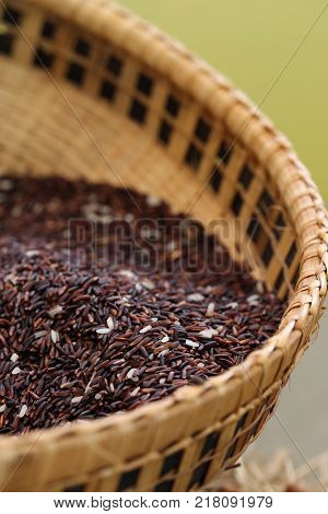 Coarse rice or half polished rice background uncooked raw cereals in bamboo wicker basket (shallow dof.)