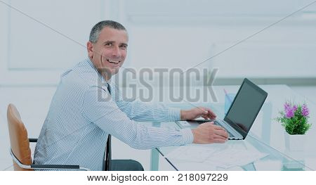 successful smiling businessman working on laptop at Desk in offi