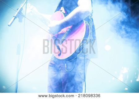 Frontman with guitar in the smoke on the stage