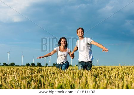 Lykkelige par kører over grainfield i sommer hånd i hånd