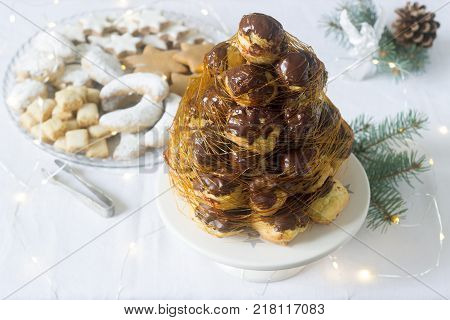 Crockembush cake and Christmas cookies in a Christmas decoration with a garland of fir branches and cones. Selective focus.