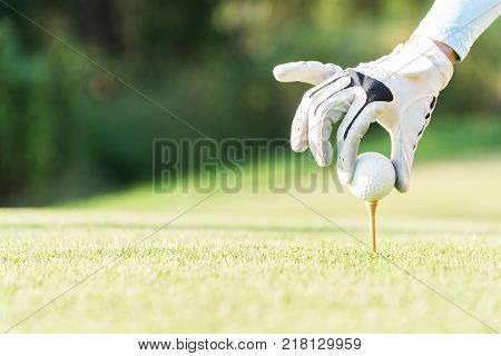 Asian woman putting golf ball on tee with golf club on sunny day for healthy sport. Lifestyle Concept.