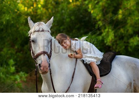the little girl lies on a white horse