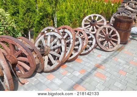 A lot of wooden wheels from old carts and cask in disorder piled in the yard.