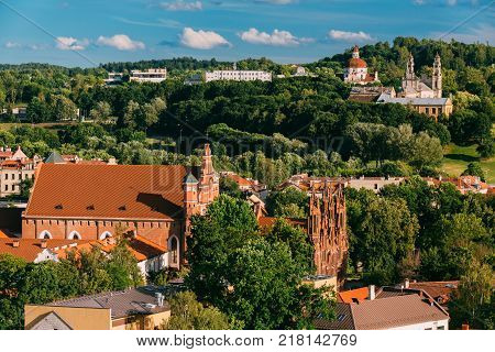 Vilnius, Lithuania. View Of Church Of St. Anne, Church of St. Francis and St. Bernard, Church Of Ascension And Church Of Sacred Heart Of Jesus Among Green Foliage In Old Town In Summer Day.