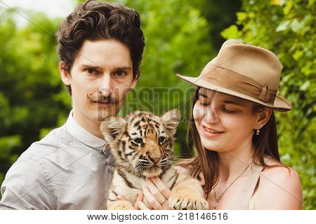 A man and woman hold tiger cub.