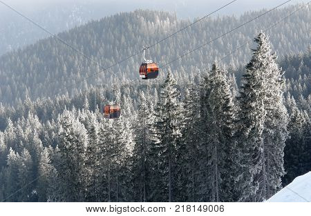 Jasna Slovakia - January 25 2017: View of two orange cabins cableway and snow-covered spruce trees in a winter forest in the ski resort of Jasna Low Tatras Slovakia.