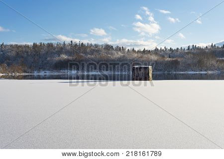 Winter landscape lake with a dam in the foreground against the forest and blue cloudy sky beautiful nature Western Ukraine