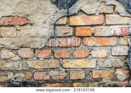 The old wall of the house. Under loose plaster exposed brick wall.
