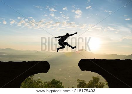 Man jump Mountain cliff sun light over silhouette
