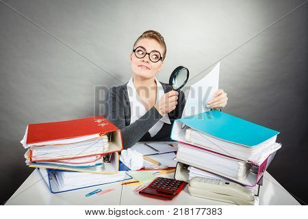 Attention paperwork corporate details workaholism concept. Crazy office lady at desk. Workaholic secretary holding magnifying glass.