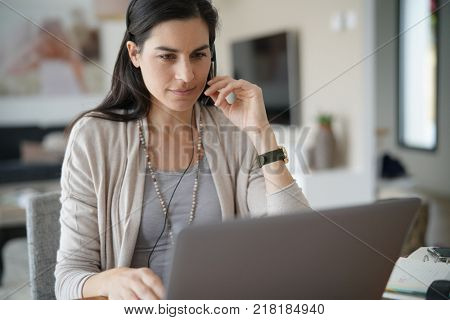 Home-office teleoperator talking on phone with headset
