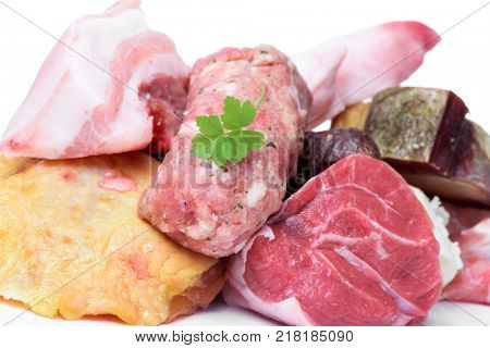 closeup of some uncooked pieces and products of chicken, beef and pork meat to prepare escudella, a soup typical of Catalonia, Spain, on a white background
